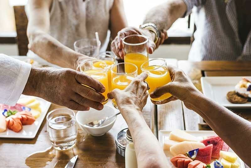 large group of people cheersing with orange juice during a breakfast meeting